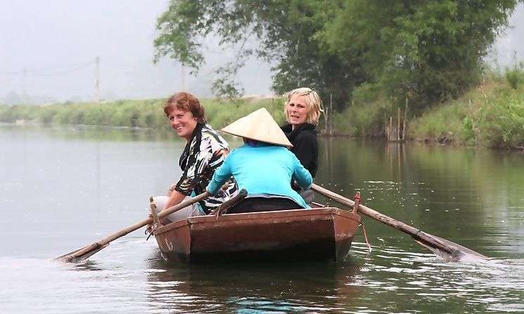 Met een houten boot vaar je over de rivier<br>